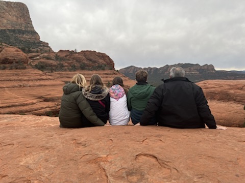 Family of five sitting on rocks with their backs to the camera
